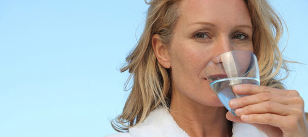 A woman drinking water with xerostomia dry mouth dentures